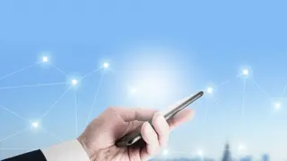 スマートフォンを持つ手と、周りに広がるネットワークの光点